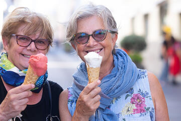 Two smiling senior women eating ice cream cones