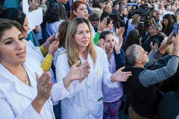 Two women in white lab coats are pictured among a large protest crowd