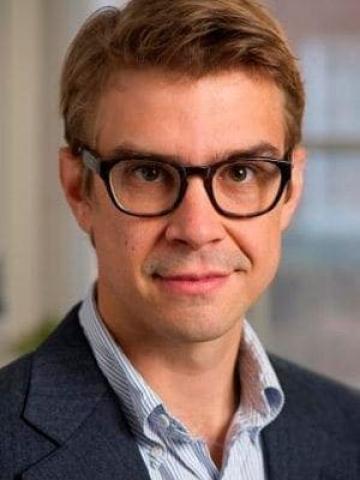Man with glasses smiles at camera